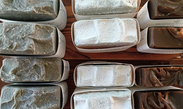 Handcrafted soap bars neatly arranged in labeled boxes on wooden shelves